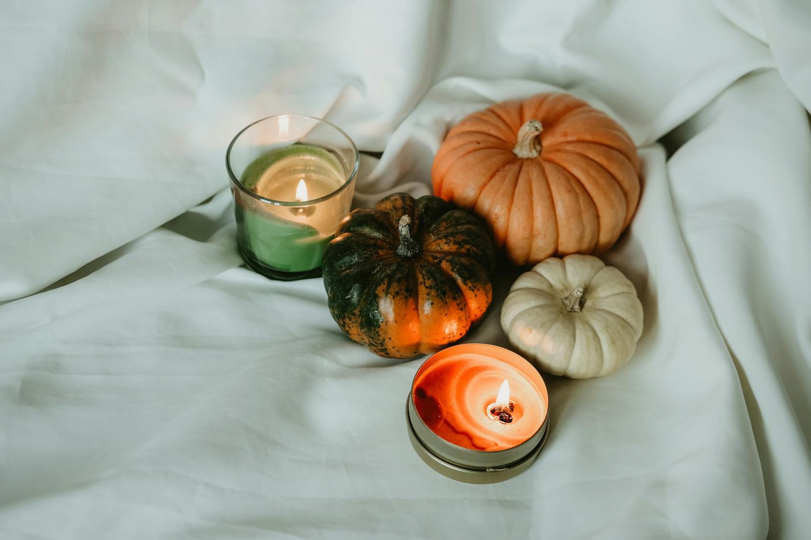 candles and pumpkins on a white sheet
