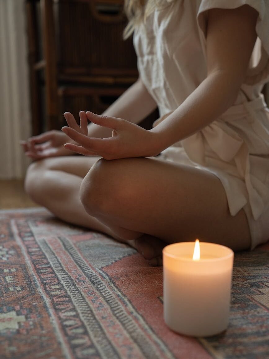 woman meditating next to a burning candle