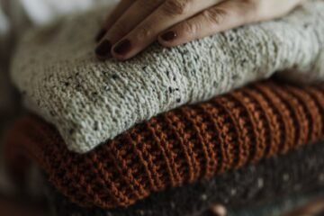 a close up shot of a person holding a stack of folded knitted fabrics